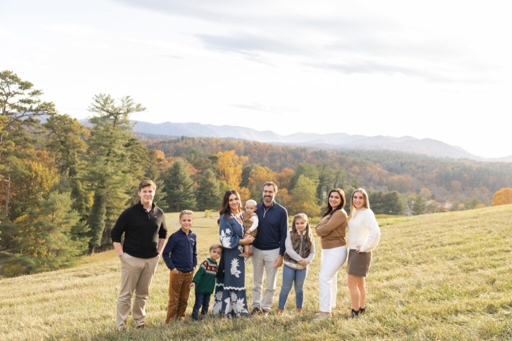 A family with many kids pose in front of the blue ridge mountains in autumn for a family photo session